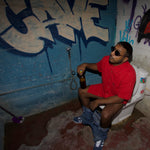 Bangalore model wearing Holystoked Bloody Mary skate shirt with his pants down, sitting on the toilet with a bottle of beer in his hands. The wall is has graffiti all over it.
